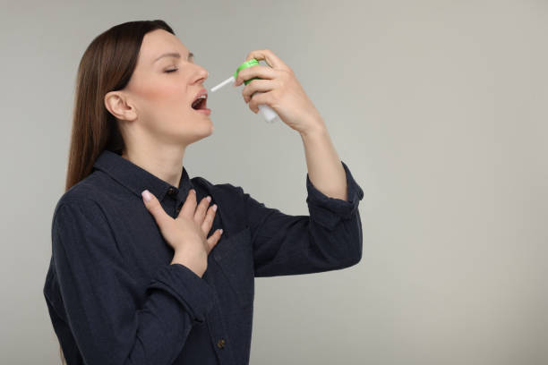 istock Woman using throat spray on grey background, space for text 2198812548