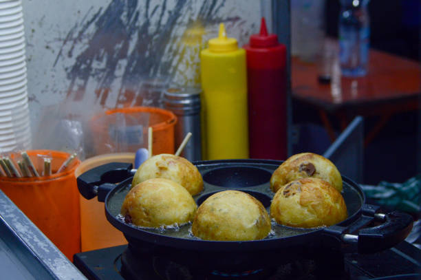 Big takoyaki being cooked Big takoyaki being cooked on a frying pan at Pasar Lama Tangerang. cooking takoyaki is a ball shaped japanese snack stock pictures, royalty-free photos & images