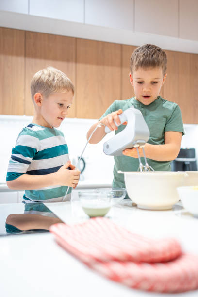 istock Caucasian Brothers Mixing Cookie Dough at Home 2198834739