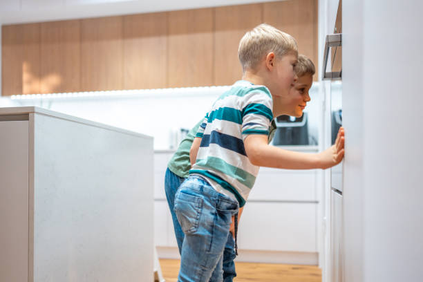 istock Curious Caucasian Boys Watch Cookies Baking in Oven 2198834812