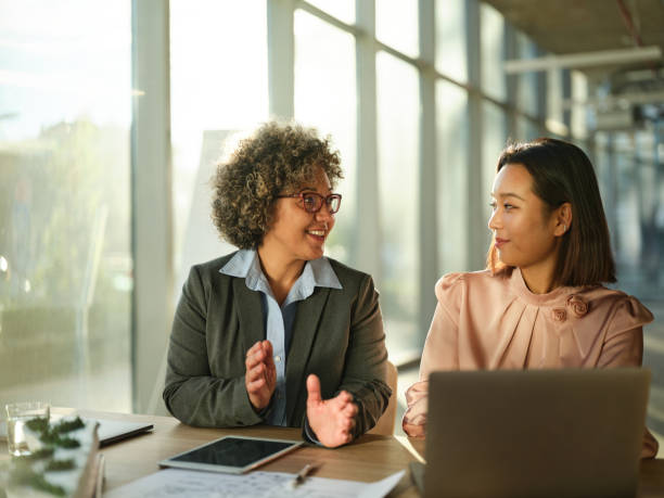 istock Happy businesswomen talking while working on laptop in the office. 2198835329