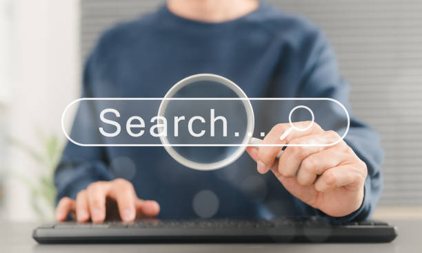 istock SEO search engine optimization concept. Person uses keyboard while holding magnifying glass with search bar labeled 
