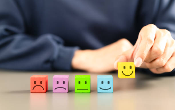 istock Customer satisfaction feedback survey concept. Person selects yellow smile face block from row of colorful blocks various facial expressions, different levels of customer satisfaction, feedback rating 2198837431