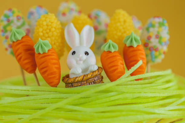 Easter Cake Decoration with Bunny and Carrots.Easter-Themed Decorated Cake. Easter cake with sugar grass, bunnies and carrots on a bright yellow background.