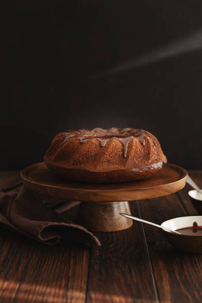 Chocolate cake with chocolate icing on dark wooden table. Low key. Front view