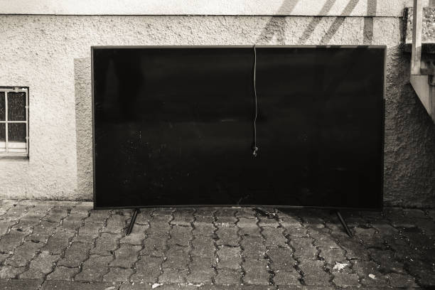 istock Large black, curvy television set resting against a textured wall outdoors in a residential area 2198846304