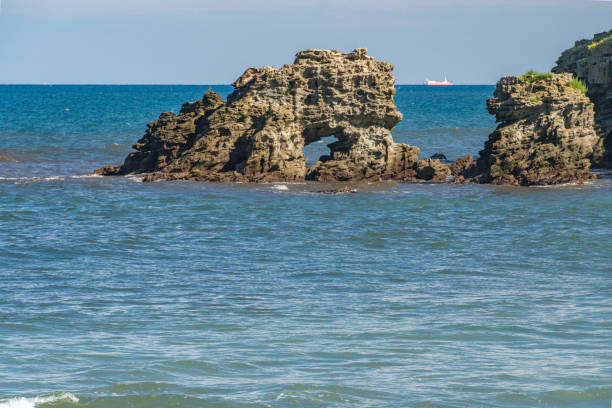 Wild beach Crvena Glavica in Montenegro. Red rocks coast arch and water waves