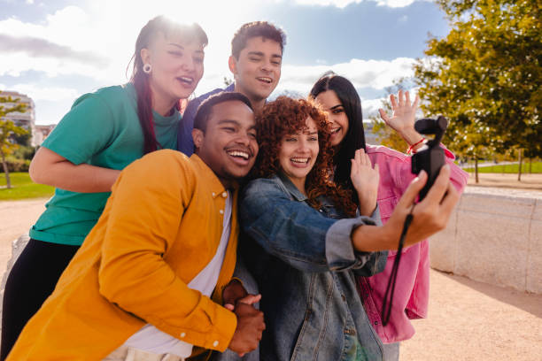istock Group of young adults taking a selfie in the park while waving 2198853043