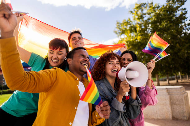 istock Happy latin activists holding rainbow flag and megaphone 2198853054