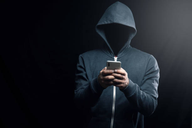 istock the hacker in the hood holds the phone 2198855845