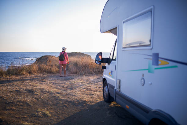 istock Wanderlust vibes: woman with straw hat walking by her camper. 2198856003