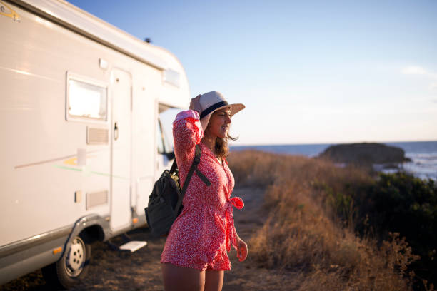 istock Morning journey: woman walking by her camper van at sunrise. 2198856009