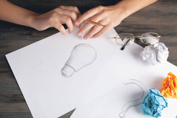 istock woman draws a light bulb on paper 2198858661