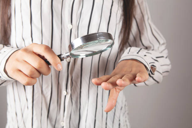 istock young woman looking at her nails with a magnifying glass 2198860764