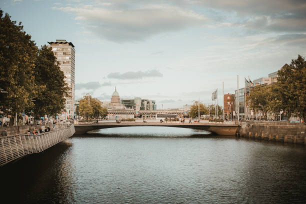 DUBLIN, IRELAND - SEPTEMBER 18, 2018: Ha'penny Bridge spanning the River Liffey in Dublin, with historic and modern architecture in the background on a calm evening.