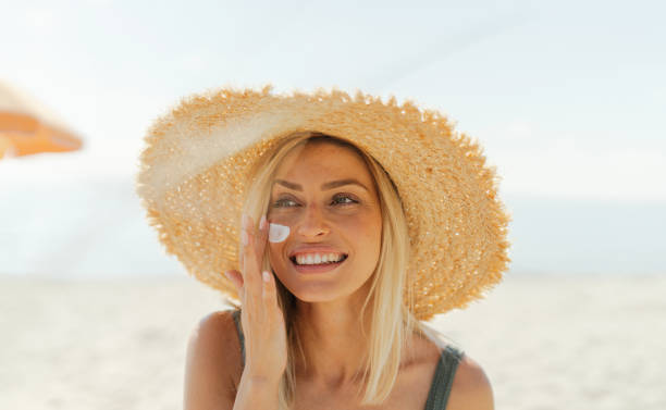 istock Young woman applying sunscreen on her face while at the beach 2198866315