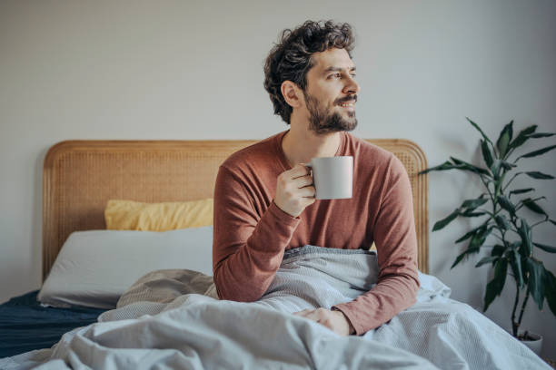 Relaxed Young handsome middle eastern man Enjoying Morning Coffee in Bed.