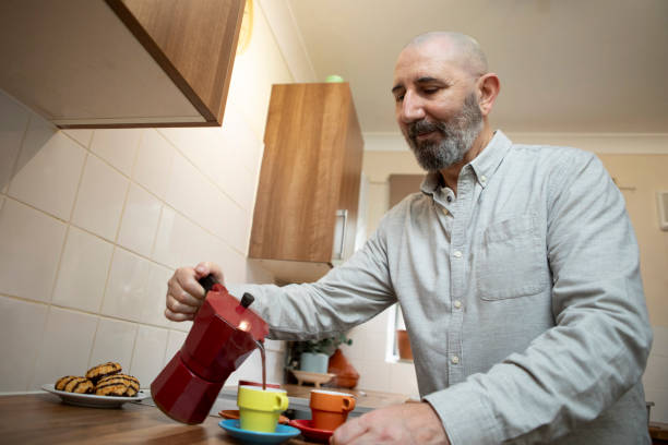 istock Mature man pouring coffee from a stovetop espresso maker into coloured cups 2198869741