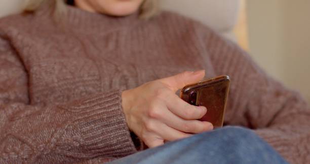 istock Individual Holding a Smartphone While Wearing a Cozy Sweater in Their Setup 2198870193