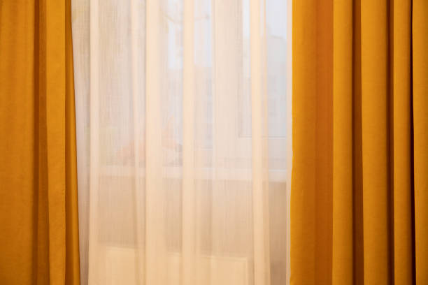 istock Dark yellow and white curtains against window in a sunny day 2198870926