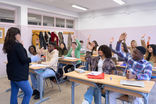 istock High school students raising hands in classroom answering teacher question 2198873359