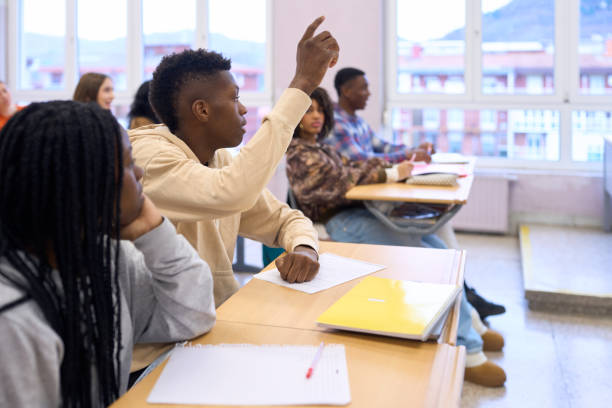 istock High school student raising hand in classroom to answer question 2198873724
