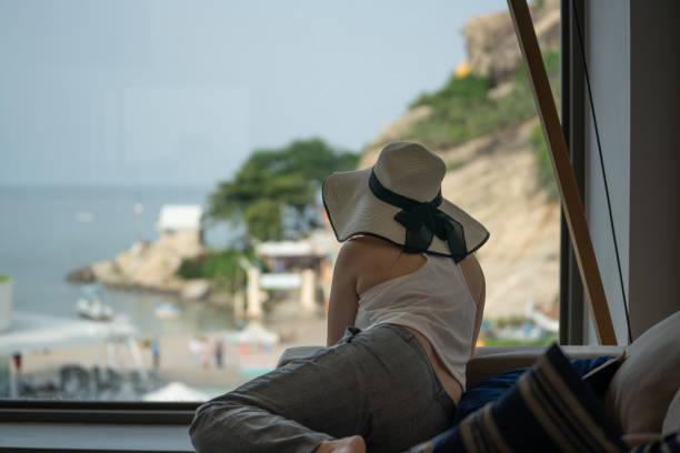 istock woman in hotel room on hat lying down for beach view 2198884162