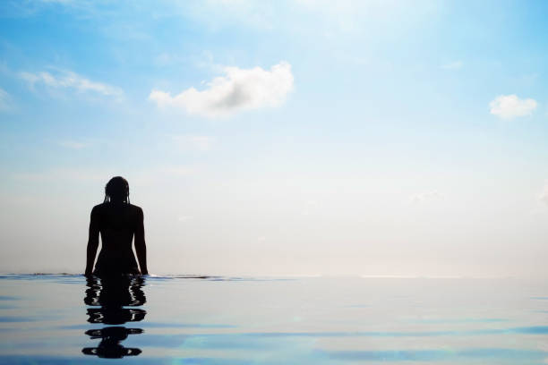 istock Woman relaxing in infinity swimming pool looking at view 2198884355