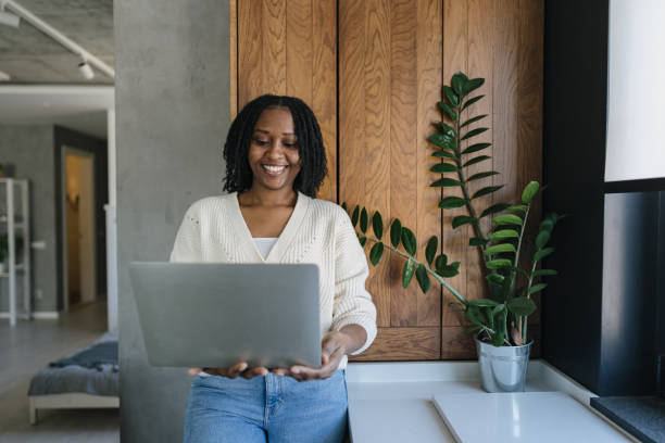 istock Smiling young woman working from home using laptop in modern kitchen 2198884776