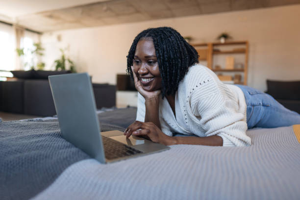 istock Young black woman lying on bed using laptop at home 2198885131