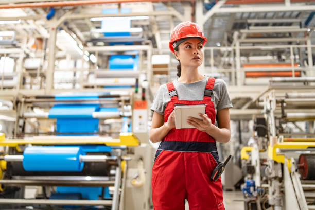 istock Industrial engineer analyzing data on tablet surrounded by large machinery in factory setting. 2198886292