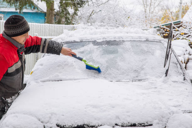 istock A man clears a car of snow 2198887394