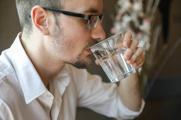 istock Handsome young man drinking water from a water glass 2198890690