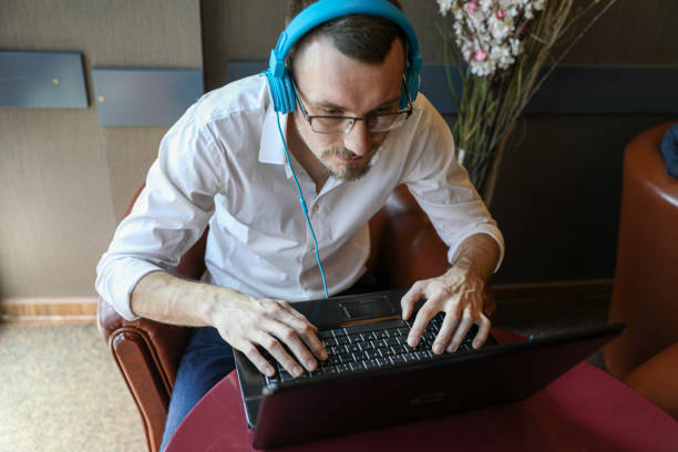 istock A young man with headphones is working on a computer and drinking coffee. 2198891638