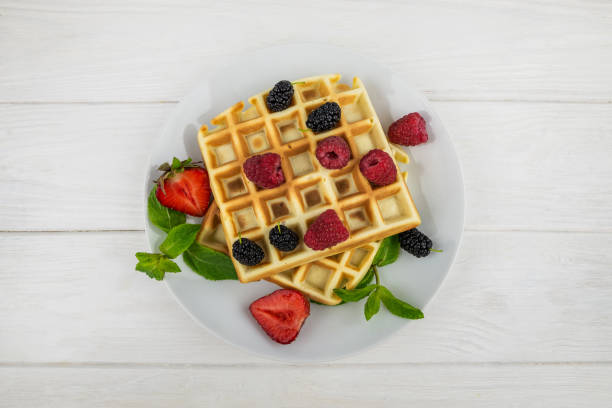 istock Belgian waffles with different berries on white.Sweet waffles in a white plate. 2198892280