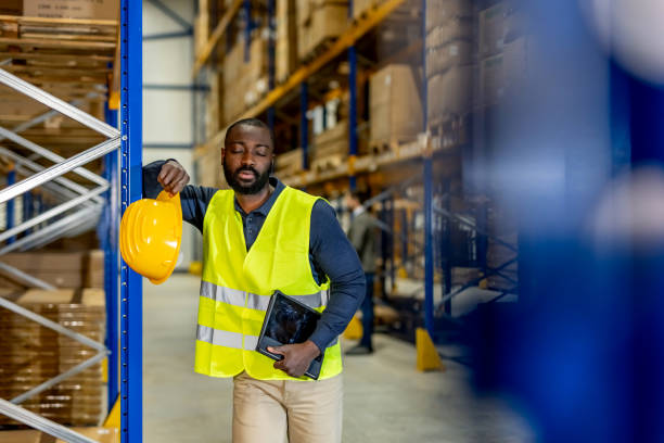 istock Warehouse Worker Taking a Break With Safety Vest and Yellow Helmet 2198895857