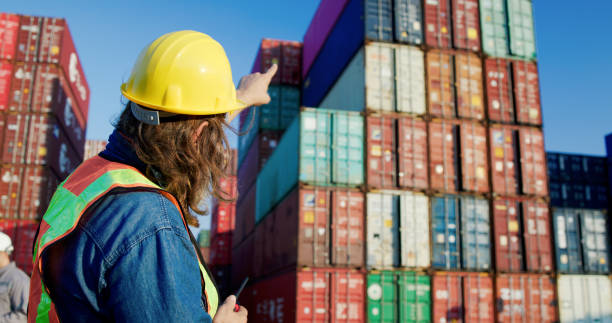 istock Senior male logistic worker  working at container warehouse shipping yard and uses walkie-talkie to communicate with his team 2198895946