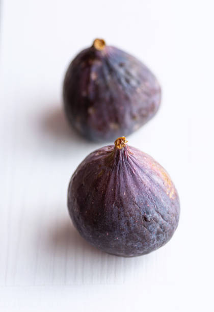 Two purple figs with on a white background. Whole fruits.