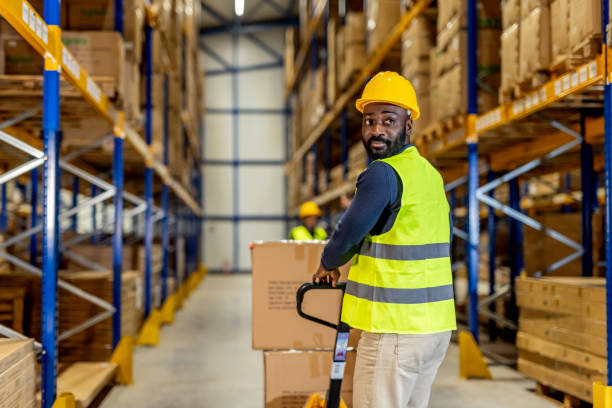 istock Warehouse Worker Using Pallet Jack to Transport Goods in Storage Facility 2198902996