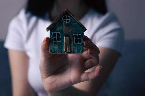 istock female hand with wooden house model 2198904202
