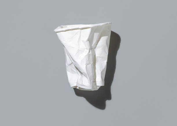istock Used and crumpled disposable white paper cup on a gray top view, hard shadow. Consumerism concept 2198904409