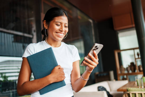 istock A Smiling Woman is Engaged with Her Smartphone While in a Modern Workspace Setting 2198906576