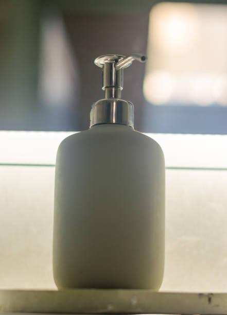Minimalist soap dispenser with metal pump in a modern bathroom interior. High quality photo