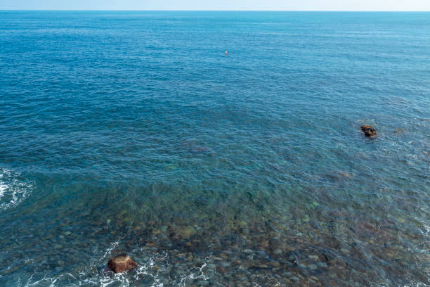 view of a seascape in Acicastello, in the province of Catania, Sicily. The black lava rock surrounds the blue of the sea