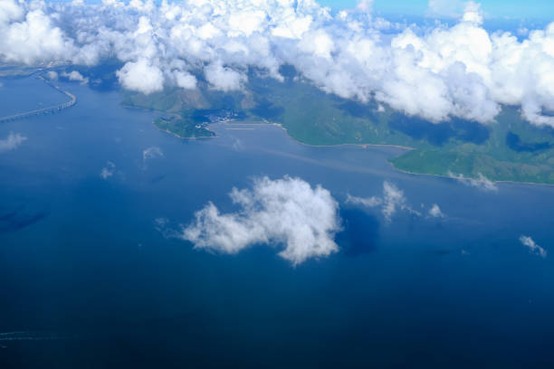 istock Looking through airplane window with the view of cloudscape. Fluffy white clouds with blue sky over the mountains in Hong Kong. 2198910629