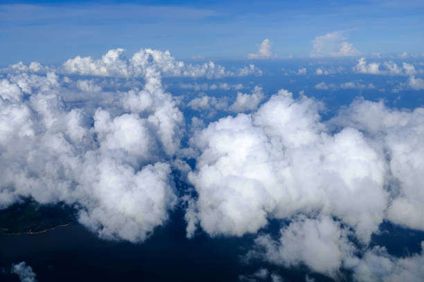 Looking through airplane window with the view of cloudscape. Fluffy white clouds with blue sky over the mountains in Hong Kong. Hong Kong rural area, Mountains from the high angle view. Nature scene.