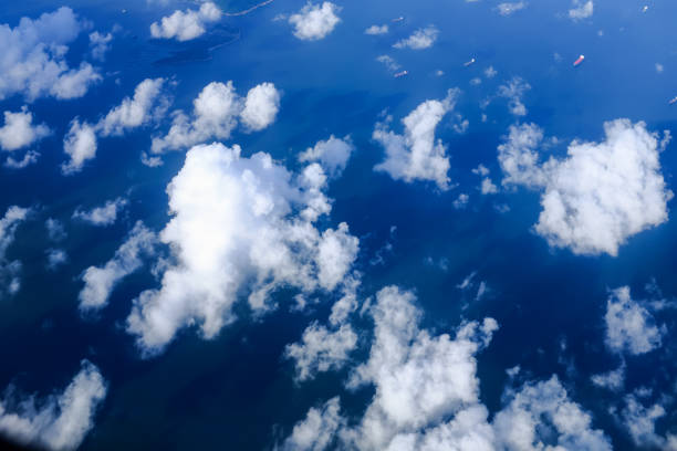 Looking through airplane window with the view of cloudscape. Fluffy white clouds with blue sky over the mountains in Hong Kong. Hong Kong rural area, Mountains from the high angle view. Nature scene.