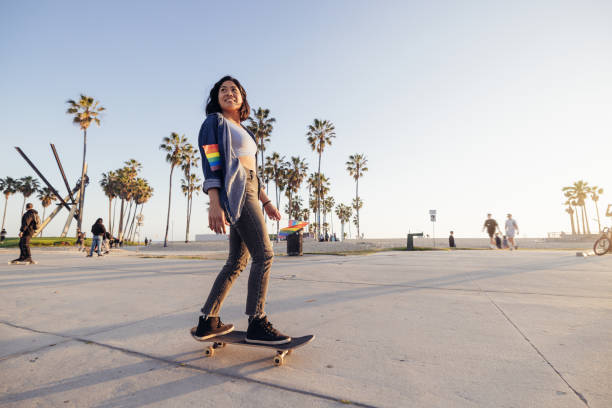 istock Woman skating to the Pride holding rainbow flags 2198911892