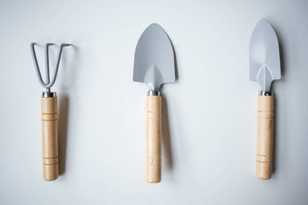 A close-up of a red-handled shovel outdoors, highlighting its use in gardening activities. The blurred background adds a depth effect, presenting a serene and natural garden atmosphere.