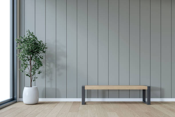 istock A minimalistic interior with a wooden bench and potted plant in front of an empty medium gray paneled accent wall background with copy space, window and decoration 2198919508